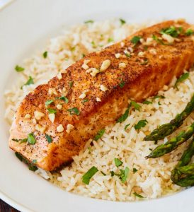 Skillet Salmon in Lemon Butter over bed of brown rice and side of asparagus on white plate