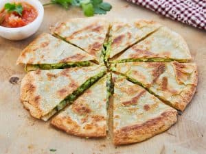 Green Goddess Quesadilla sliced with a side of salsa on wooden surface