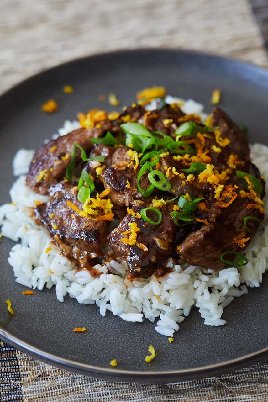 Skillet Orange Beef served over white rice on a gray plate