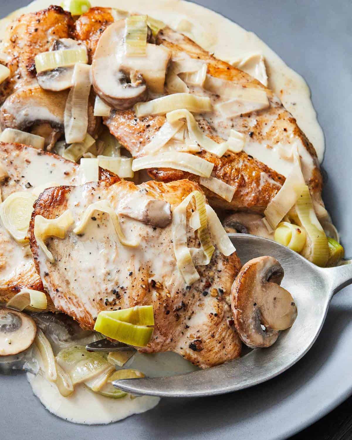 Creamy Chicken with Leeks and Mushrooms on a gray plate with serving spoon