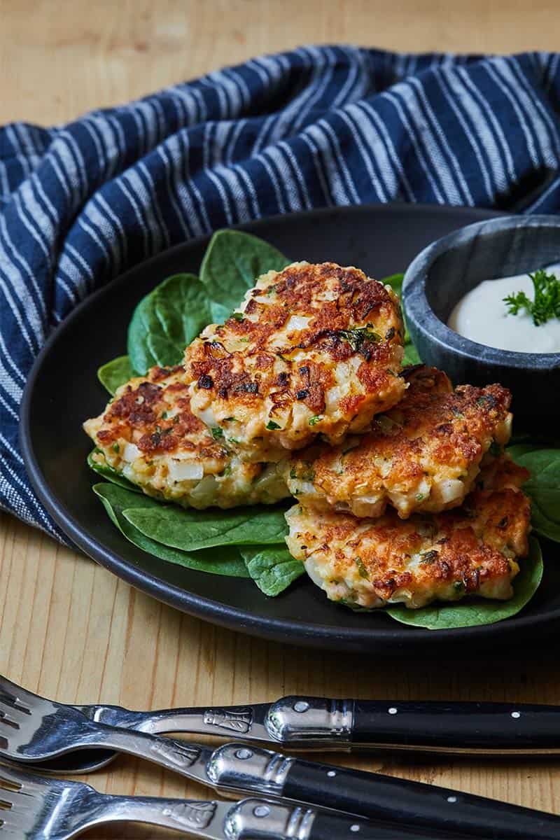 Healthy Salmon Cakes on black plate with a side of sauce