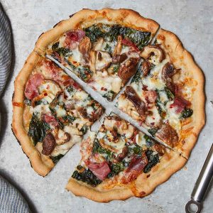 Kale Mushroom Pizza sliced into quarters on a metal surface