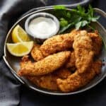 Air fryer chicken tenders in a platter with dipping sauce.