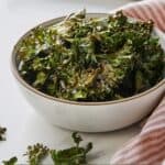 Pinterest graphic of a bowl of kale chips being a pink and white linen.
