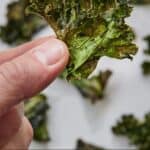 Pinterest graphic of a hand holding up a piece of kale chip.