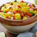 Pinterest graphic of lime being squeezed onto a bowl of mango salsa.