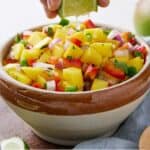 Pinterest graphic of a bowl of mango salsa with a lime squeezed on.