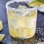 Pinterest graphic of a glass of skinny margarita with a lime wedge and ice cubes.