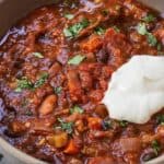 Pinterest graphic of a close up photo of a bowl of vegetarian chili with sour cream on top.