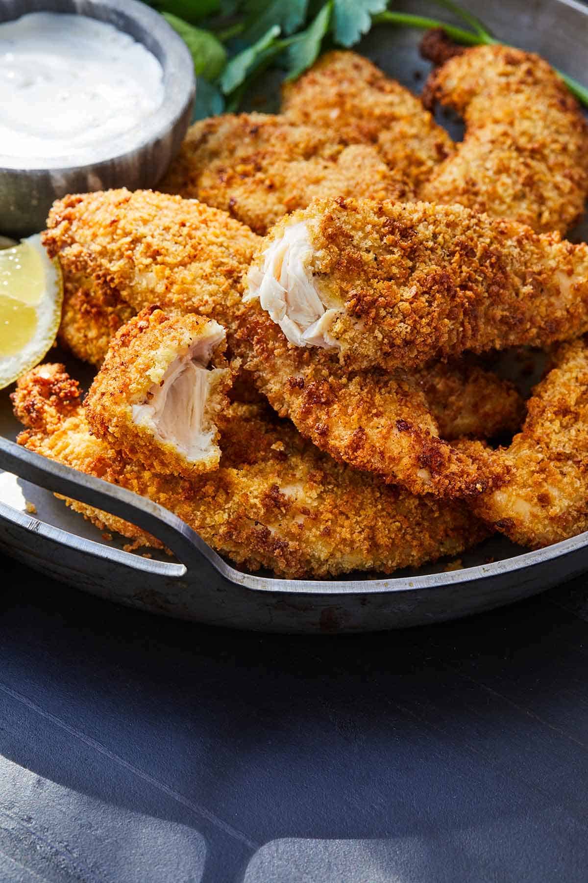 A platter of air fryer chicken tenders with one cut in half.