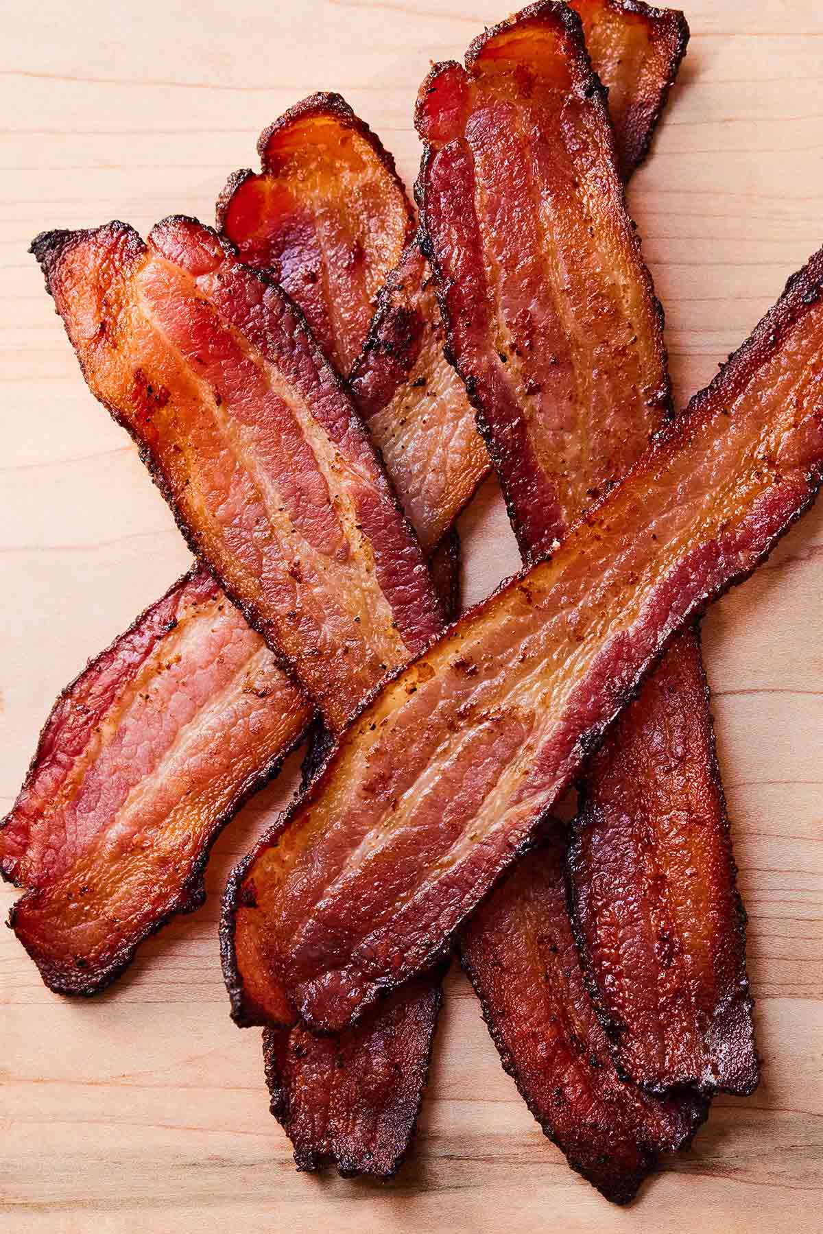 Five strips of bacon on a cutting board.