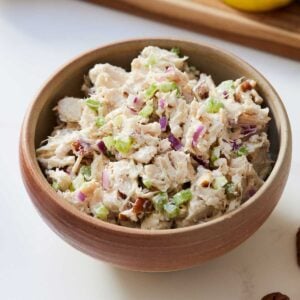 Close up of a bowl of chicken salad on a marble surface.