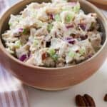 Pinterest graphic of a bowl of chicken salad containing chicken, pecans, celery, and red onions.