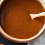 Pinterest graphic of a spoon inside of a bowl of enchilada sauce.