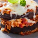 Pinterest graphic of a close up of eggplant parmesan topped with basil.