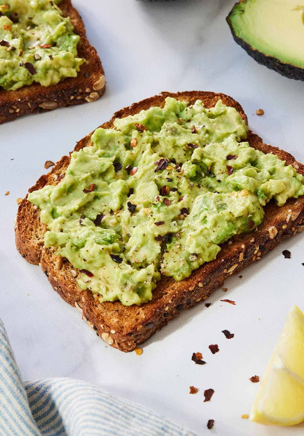 A slice of avocado toast with red chili flakes on top
