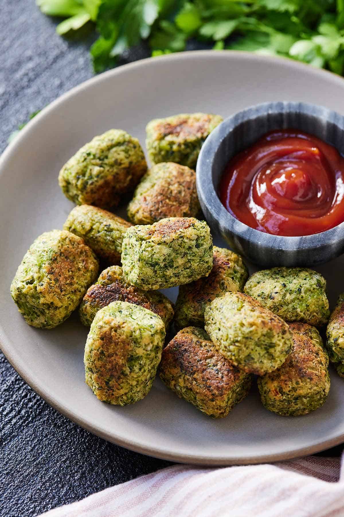 Broccoli tots in a plate with ketchup beside it.