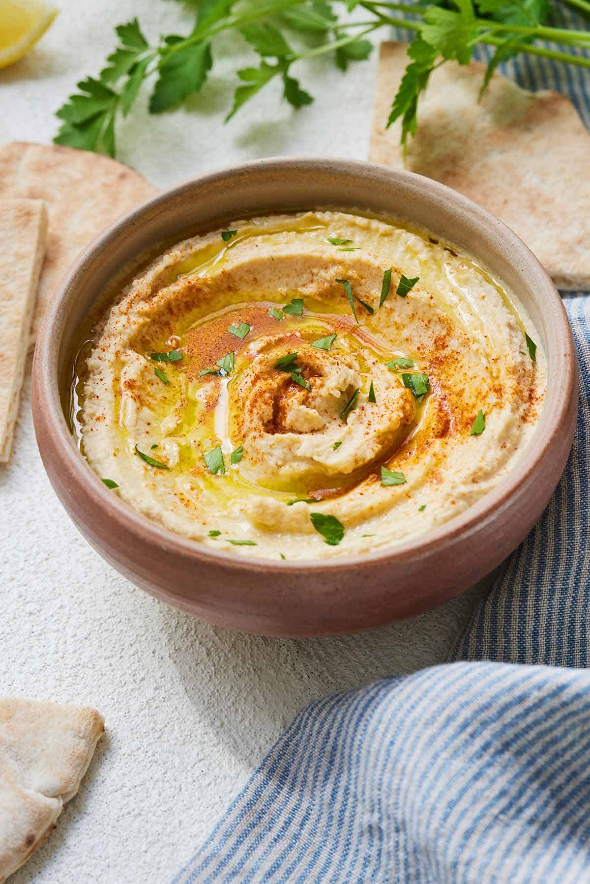 A bowl of hummus garnished with fresh herbs, paprika, and olive oil.