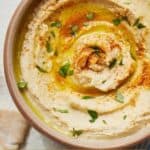 Pinterest graphic of an overhead view of a bowl of hummus with a swirl with olive oil and paprika.