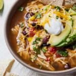 Pinterest graphic of a bowl of Instant Pot chicken tortilla soup topped with chips, sliced avocado, and sour cream.