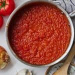 Pinterest graphic of an overhead view of a pot of marinara sauce with ingredients strewn around the pot.