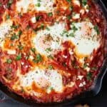 Pinterest graphic of a close up of shakshuka in a cast iron pan.