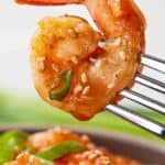 Pinterest graphic of a single sweet and sour shrimp held up by a fork with sesame seeds and green onions.