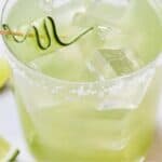 Pinterest graphic of a close up of a glass of cucumber margarita with ice and a cucumber ribbon.