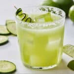 Pinterest graphic of a salt-rimmed glass of cucumber margarita with cucumber slices and lime wedges around.