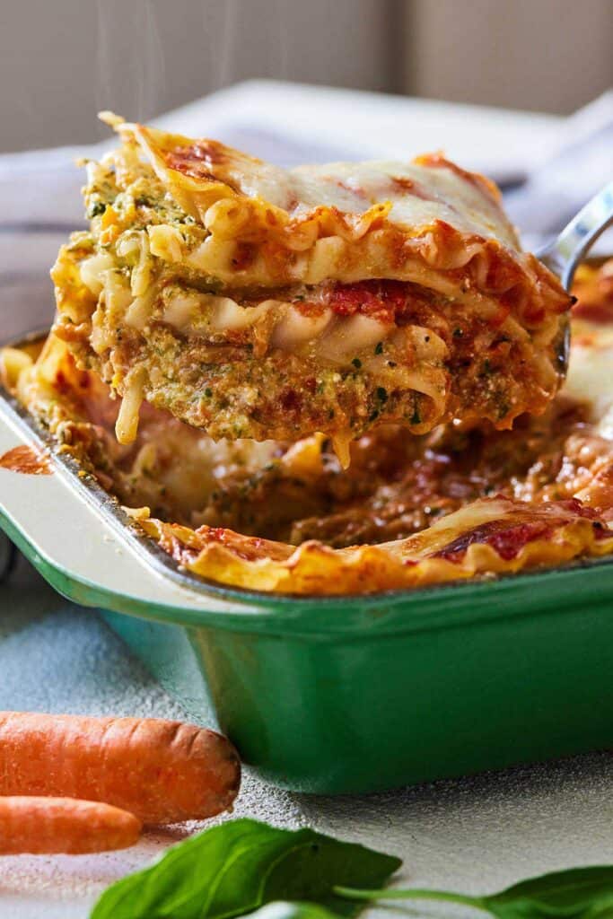 Close up of a serve of lasagna being lifted out of the pan with a spatula.