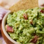 Pinterest image of a bowl of guacamole with a tortilla chip stuck into the dip.
