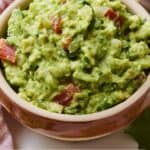 Pinterest image of a bowl of guacamole with tortilla chips in the background.