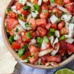 Pinterest image of an overhead view of a brown bowl of pico de gallo beside some chips and a lime wedge.