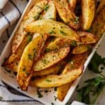 Pinterest graphic of air fried potato wedges in a white bowl with fresh herbs on top.