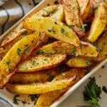 Pinterest graphic of a bowl of air fryer potato wedges with fresh herbs as garnish.