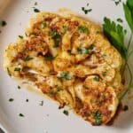 Close up of a cauliflower steak with fresh parsley as garnish.