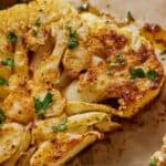 Pinterest graphic of a close up view of a cauliflower steak with fresh chopped parsley on top.