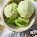 Pinterest graphic of an overhead view of a bowl of multiple scoops of avocado ice cream with mint on top.