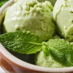 Pinterest graphic of a close up view of three scoops of avocado ice cream in a bowl with some mint.