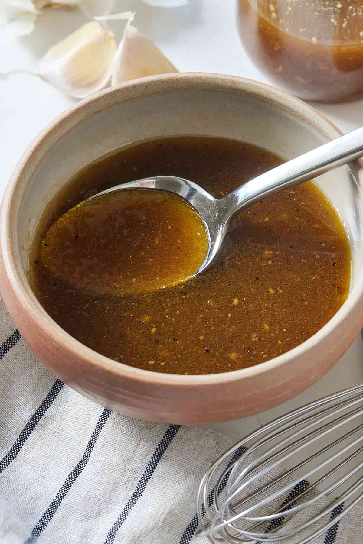 A small bowl with balsamic vinaigrette and a spoon inside of it.