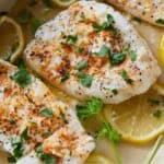 Pinterest graphic of the baked cod in a baking dish with lemon slices and fresh chopped parsley.