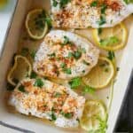 Pinterest graphic of an overhead view of a baking dish with three pieces of cod with fresh herbs and lemon slices.