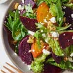 Pinterest graphic of an off center plate of beet salad with a small bowl of salad dressing on the side.