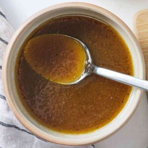 Close up of a bowl of balsamic vinaigrette with a spoon inside.