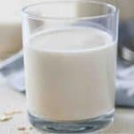 Pinterest graphic of a glass of oat milk with a blue linen napkin in the background.