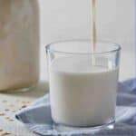 Pinterest image of a glass with oat milk being poured into it.