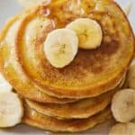 Pinterest graphic of an overhead view of a stack of pancakes with sliced bananas and syrup.