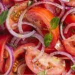 Pinterest graphic of a close up image of tomato salad with cut tomatoes and sliced red onions.