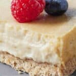 Pinterest graphic of a close up of a cut cheesecake with a raspberry and blueberry on top.