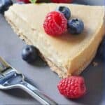 Pinterest graphic of the overhead view of a slice of vegan cheesecake with raspberries and blueberries on top and around the cheesecake.